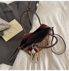 Close-up of leopard print tote bag with brown handles and a cute bear plush keychain