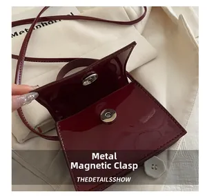 Detail shot of the magnetic snap closure on a wine red patent leather mini bag