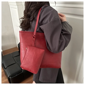 Detail of red leather tote bag with matching detachable small zipper pouch and slim straps