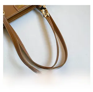 Detail of caramel leather tote handle with decorative printed silk scarf and white stitching