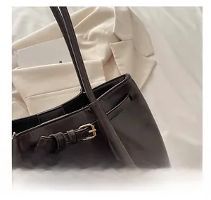 Close-up of deep coffee tote bag with gold buckle detail and minimalist leather texture