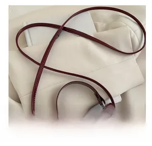 Close-up of glossy dark red shoulder strap and sleek patent leather texture on a bag