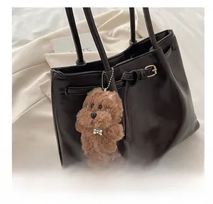 Close-up of fluffy brown dog charm with TOP DOG tag on a premium leather tote bag
