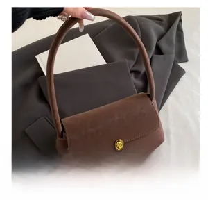 Detail of dark brown suede handbag with golden metal clasp on a textured background
