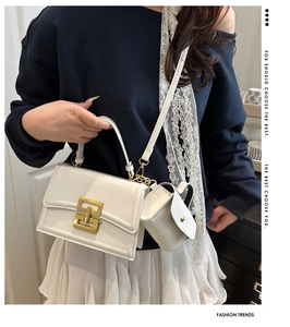 Detailed close-up of white leather crossbody bag with distinctive gold geometric metal buckle