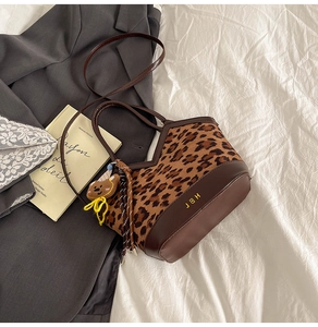 Detail of retro leopard print bucket bag with leather stitching and plush bear charm