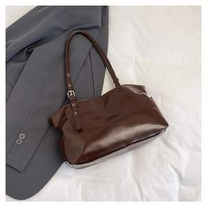 Close-up of deep brown patent leather tote with adjustable silver metal buckle straps
