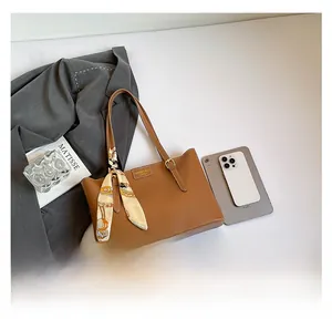 Detailed top view of brown leather tote bag with silk scarf and office essentials