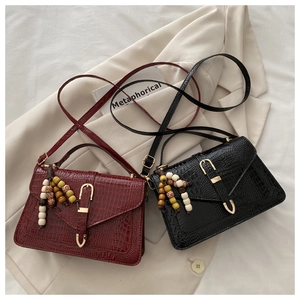 Detail of crocodile pattern handbags in wine red and black with colorful bead pendants