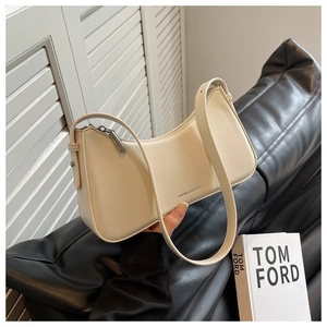 Detailed close-up of a cream faux leather hobo shoulder bag with a metal zipper closure