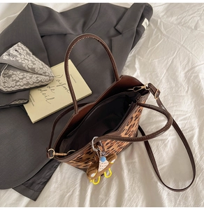Macro detail of leopard print bucket bag with brown leather strap and bear charm