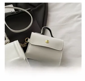Close-up of a white mini leather bag charm with a gold snap buckle and metal chain detail