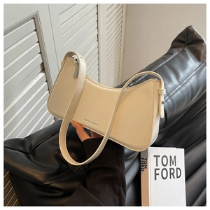 Detail of a creamy beige faux leather hobo bag with silver zipper on a black sofa