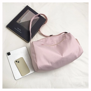 Flat lay of pink nylon fitness bag with zipper and adjustable strap next to a tablet