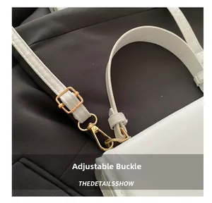 Detail view of white leather bag featuring adjustable gold metal buckle and lobster clasp