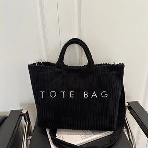 Large black corduroy tote bag with white TOTE BAG lettering and long shoulder strap
