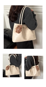 Detail of cream tote bag with knot accent and plush dog pendant on shoulder strap