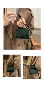 Detail of dark green patent leather mini crossbody bag with glossy finish and carry handle