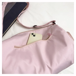 Detailed view of pink nylon gym bag featuring a functional front zipper pocket for phone