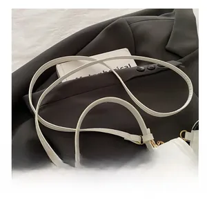 Detail of adjustable white leather shoulder strap with gold metal buckle and hook