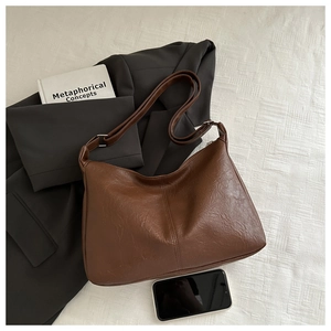 Sac fourre-tout en cuir marron vintage avec blazer gris et smartphone sur tissu texturé