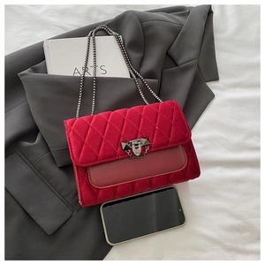 Detailed view of red velvet quilted handbag with silver chain strap and metal buckle