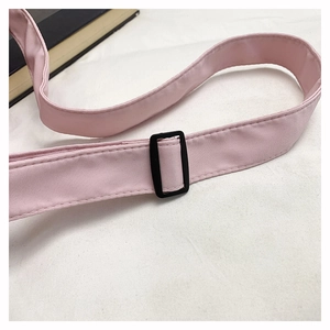 Detail of light pink shoulder strap with black adjustable buckle and neat stitching