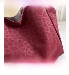 Macro shot of matte leopard print pattern on burgundy synthetic leather tote bag