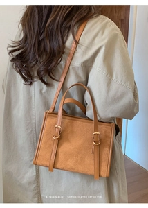 Dettaglio della borsa tote retrò marrone caramello con fibbie dorate su un trench coat