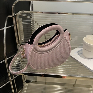 Pink glitter semicircular handbag with top handle and gold hardware on a display shelf