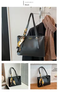 Detail of black leather tote bag with white contrast stitching and printed silk scarf