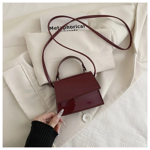 Macro detail of wine red patent leather mini handbag with glossy finish and top handle