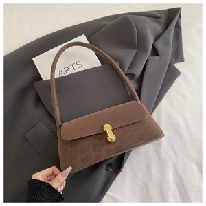 Detail of leopard print suede shoulder bag with gold metal lock on a gray blazer