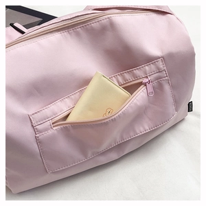 Detail of pink nylon shoulder bag showing front zipper pocket and functional card storage