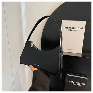 Close-up of black polished leather hobo bag with white brand logo and zipper detail
