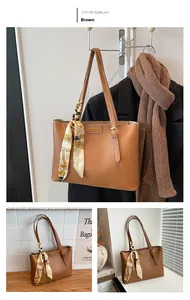 Brown leather tote bag detail with silk scarf handle and embossed fashion logo tag