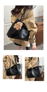 Detail of black leather tote bag featuring side buckle and cute brown bear pendant
