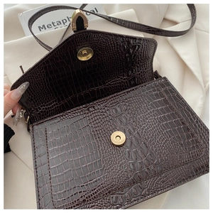 Detail of dark brown crocodile textured bag with gold magnetic buckle and inner flap