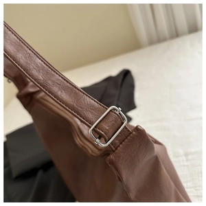 Détail de la bandoulière réglable avec boucle argentée sur un sac cabas en cuir marron