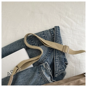 Detail of adjustable nylon shoulder strap and buckle on khaki crossbody bag