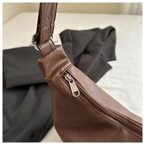 Gros plan sur la fermeture éclair argentée et les coutures d'un sac cabas en similicuir marron