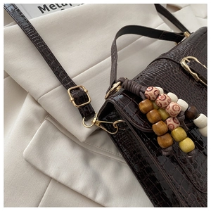 Detail of dark brown crocodile texture handbag with colorful ethnic wooden bead tassels