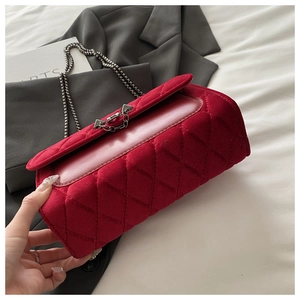 Detail of dark red velvet quilted handbag with grey metal chain and triangle buckle
