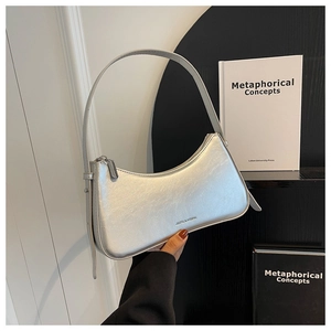 Detail of silver metallic leather underarm bag with adjustable strap and zipper closure