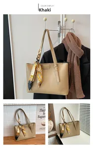 Detail of khaki tote bag with floral silk scarf handle and adjustable strap on display