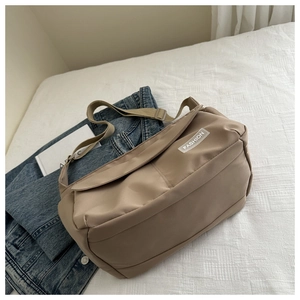 Detail of khaki nylon messenger bag with fashion label on white fabric background