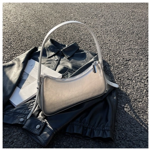 Detail of silver metallic baguette bag with leather strap on black leather jacket background