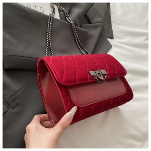 Close-up of red velvet quilted crossbody bag with silver lock and chain strap