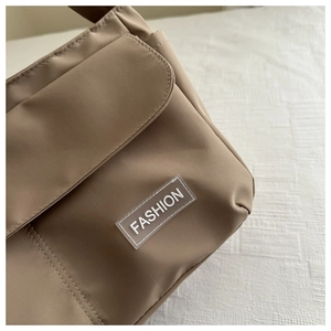 Detail view of khaki nylon crossbody bag with magnetic flap and PVC fashion patch