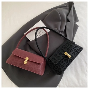 Close-up of leopard print baguette bags with gold twist locks on grey blazer